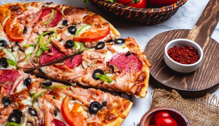 side-view-pizza-with-salami-ham-green-peppers-tomatoes-black-olives-cheese-table (1)